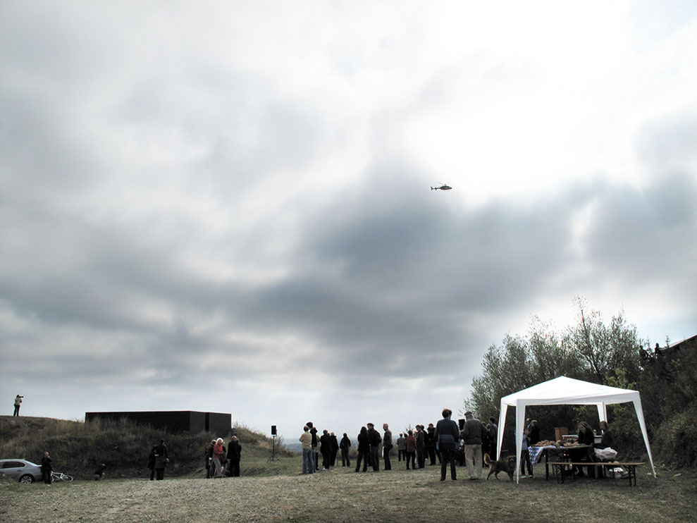 A Performer is flying in a Helicopter Bell 407 and looking at the exhibition from above for 2-3 minutes and then flying away.