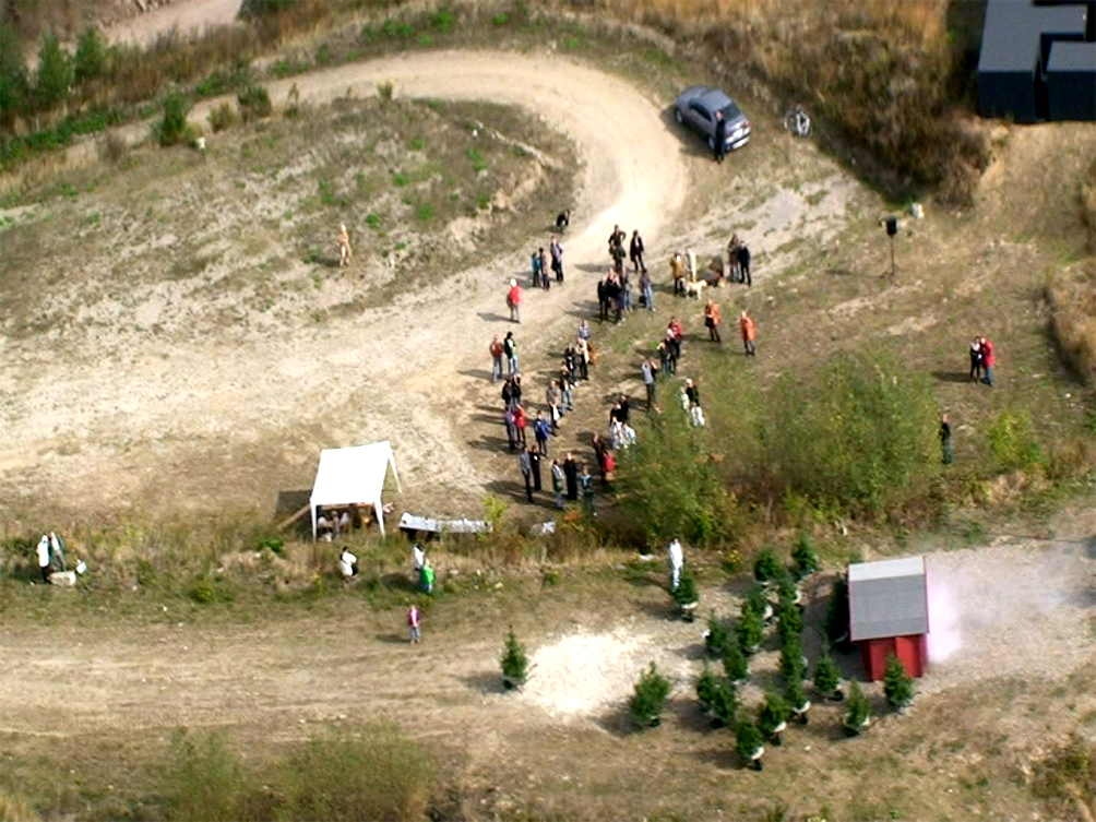 A Performer is flying in a Helicopter Bell 407 and looking at the exhibition from above for 2-3 minutes and then flying away.