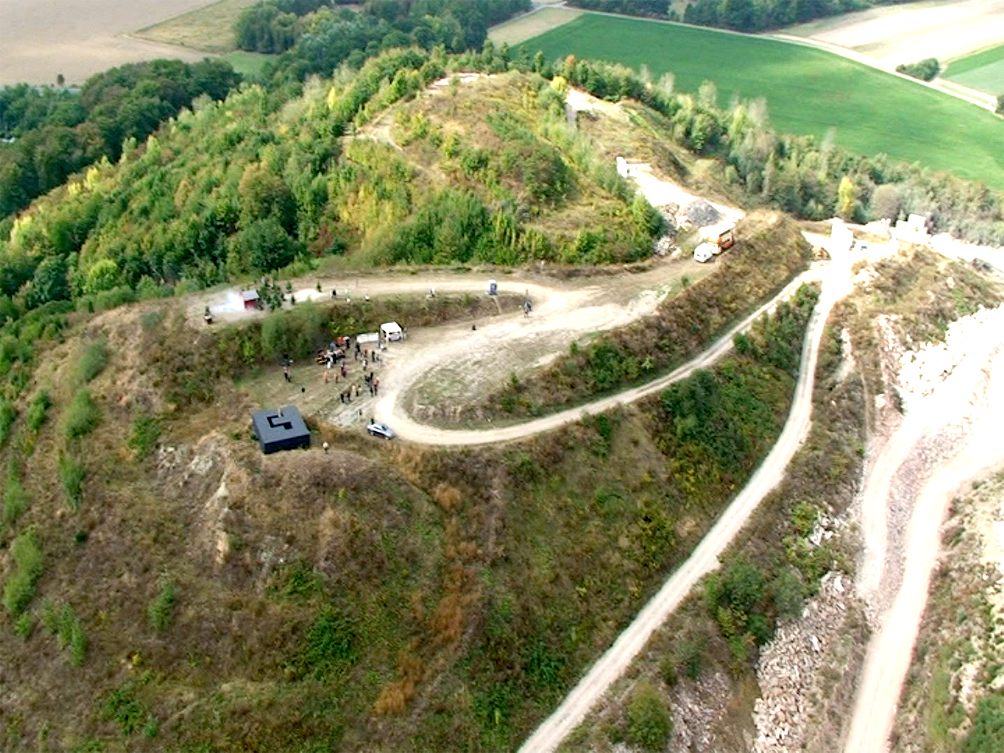 A Performer is flying in a Helicopter Bell 407 and looking at the exhibition from above for 2-3 minutes and then flying away.
